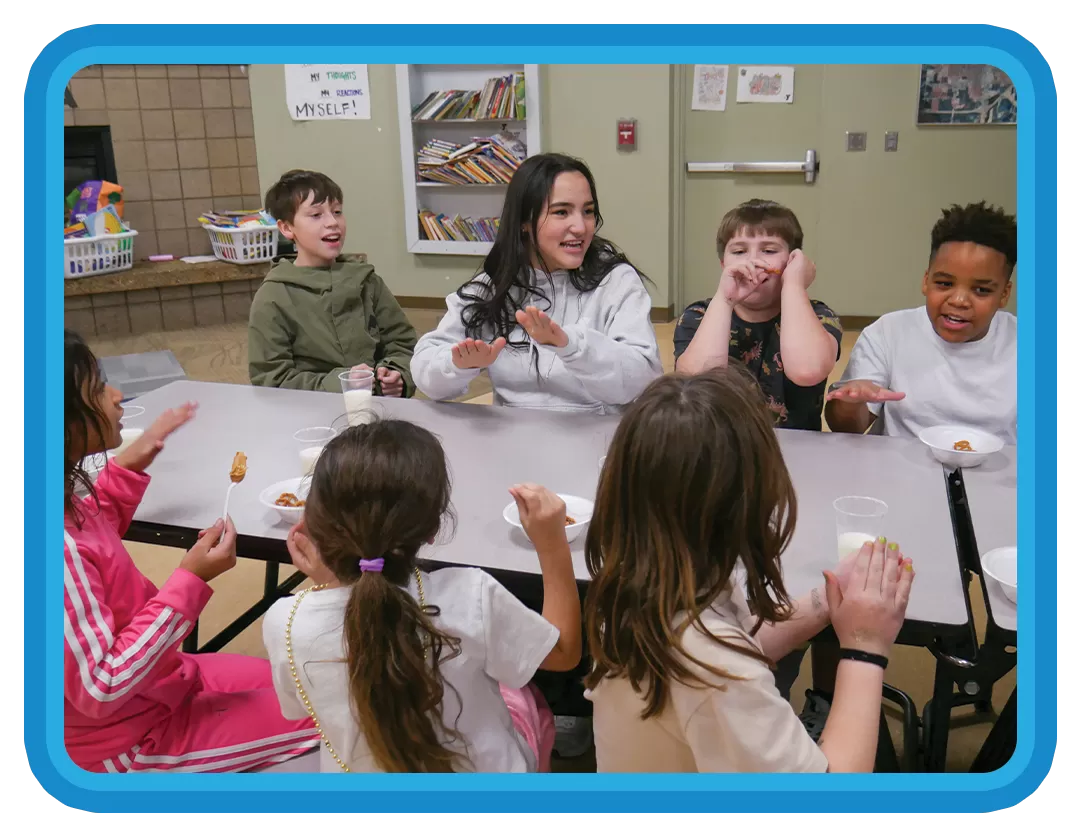 children and YMCA leader enjoying  snack time
