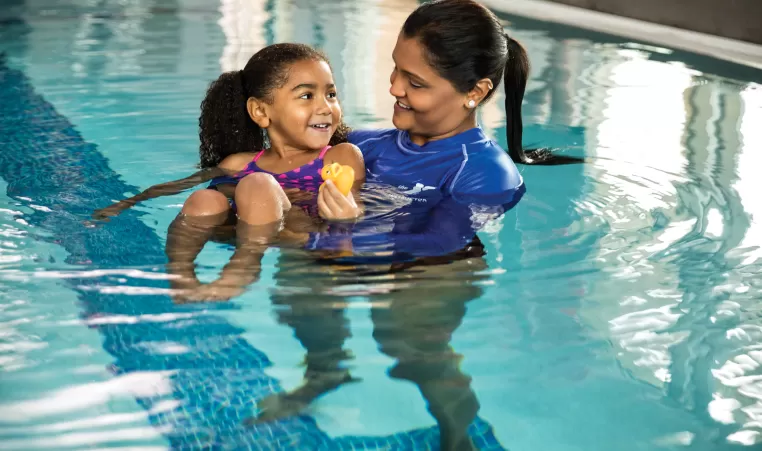 happy child taking a swim lesson with a YMCA instructor